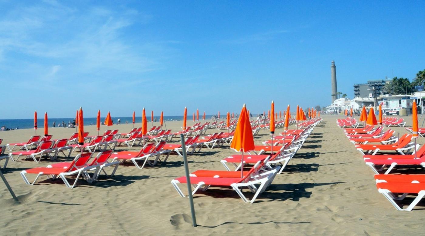 Strand på Gran Canaria med tomme solsenger og parasoller. Kanariøyene vinner vinterturister og kan tape sommertrafikk